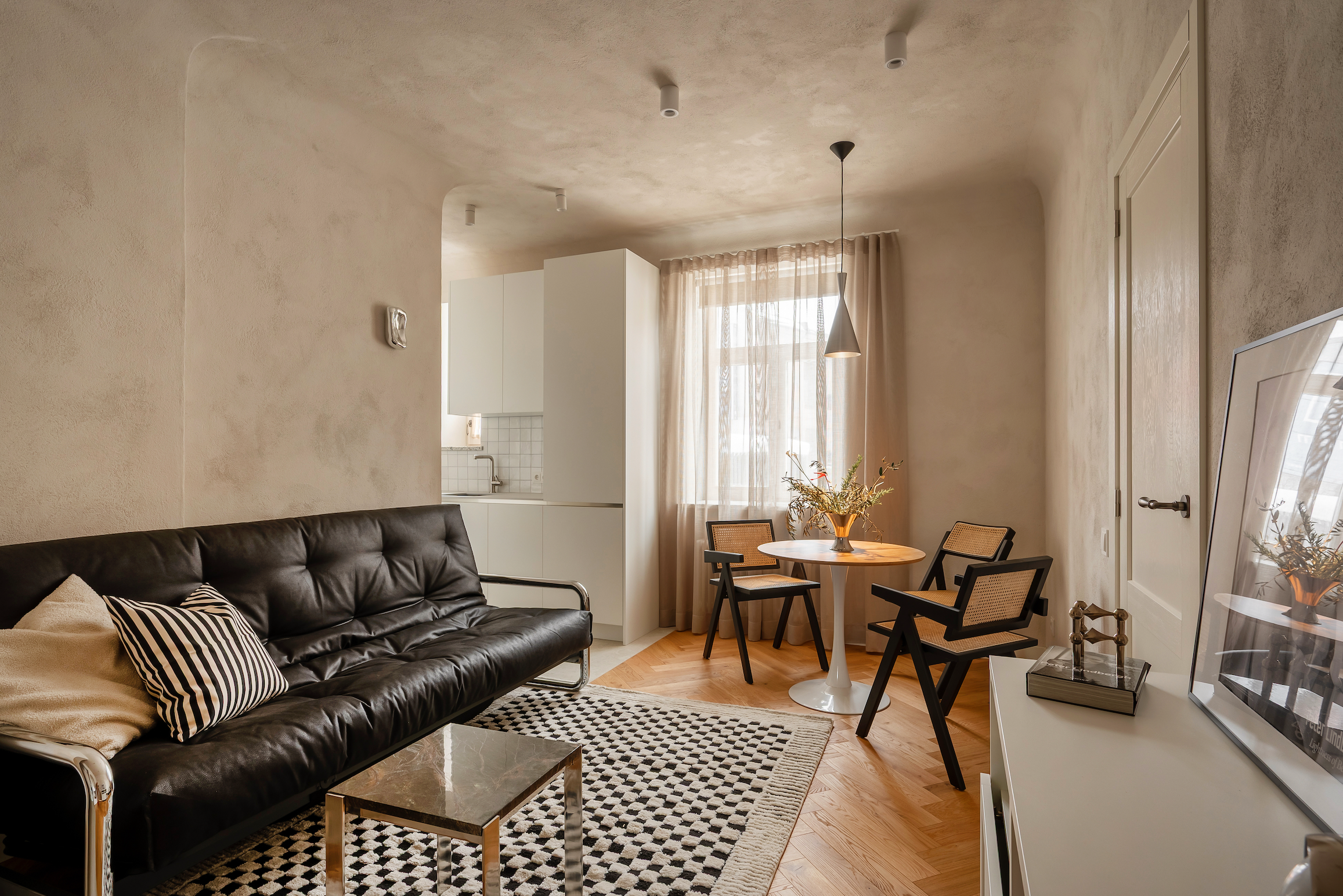 Modern living room with a black leather sofa, coffee table, and decorative elements. Limewash wall effect from Kulta Lime Paints.