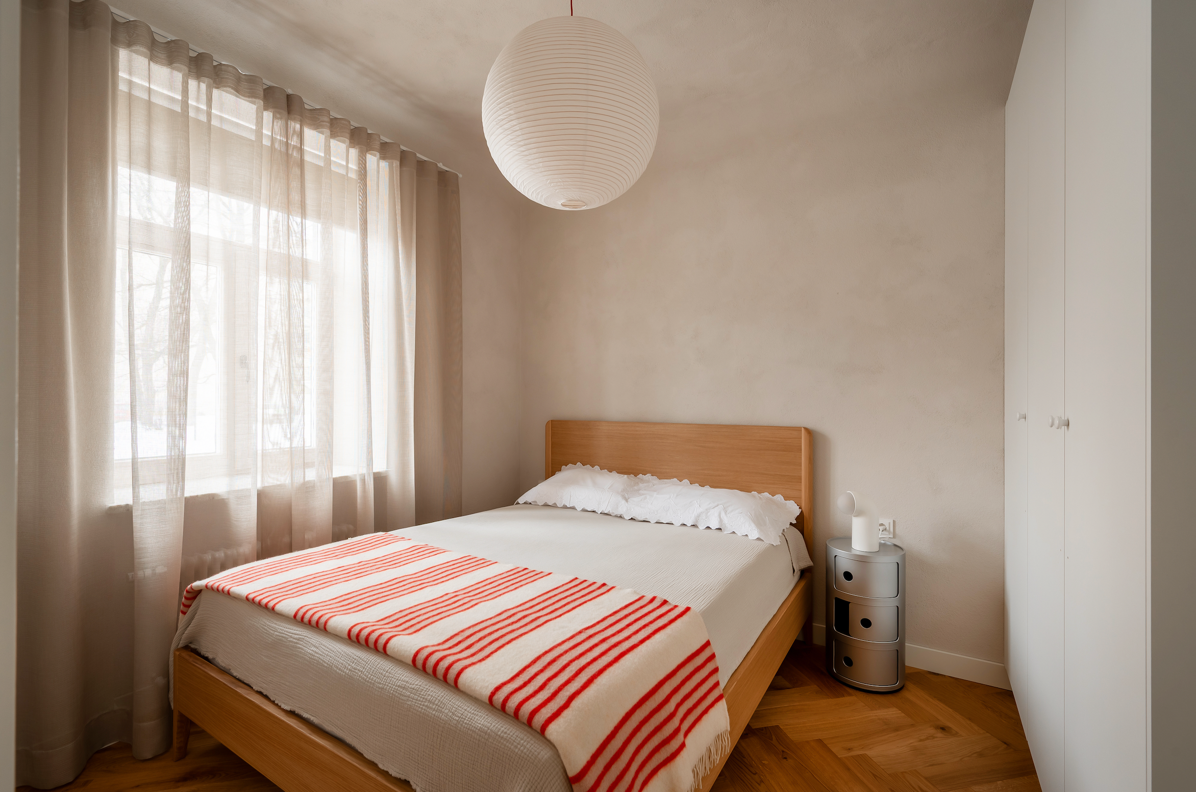 Bedroom with a bed, striped blanket, and nightstand. Limewash effect on the walls with Kulta Lime Paint.